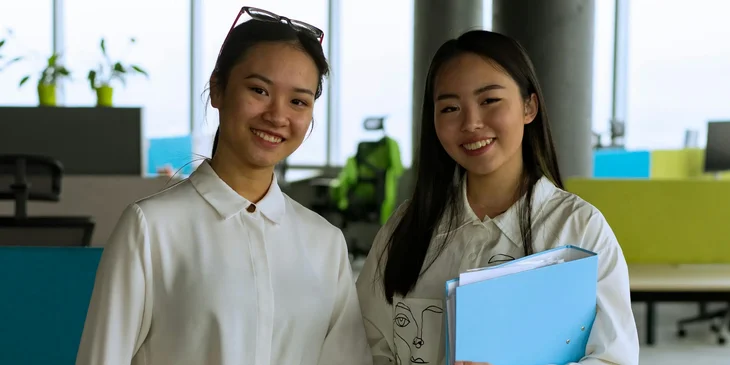 A woman in white long sleeve shirt holding a binder.