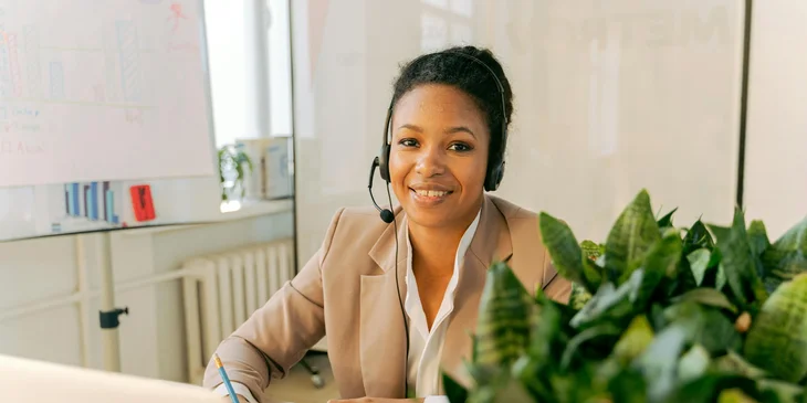 A woman wearing a headset while sitting in front of a laptop.