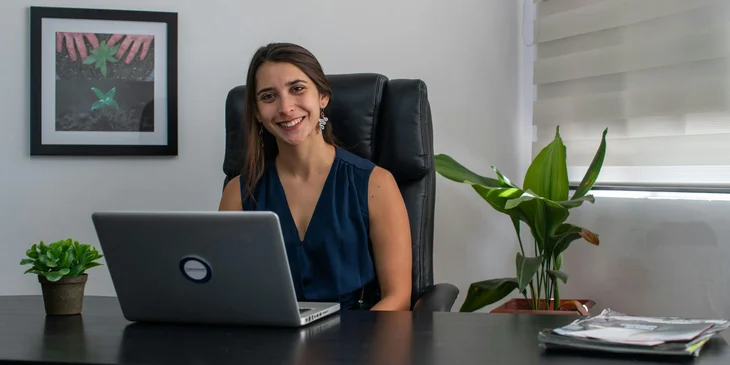 A senior account executive sits at her desk, smiling.