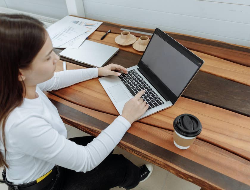 A senior internal auditor typing on a laptop at their desk.