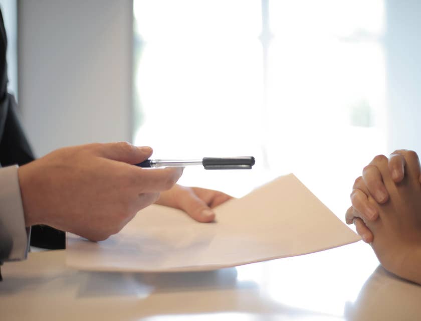 Colleague handing a contract and pen to a coworker