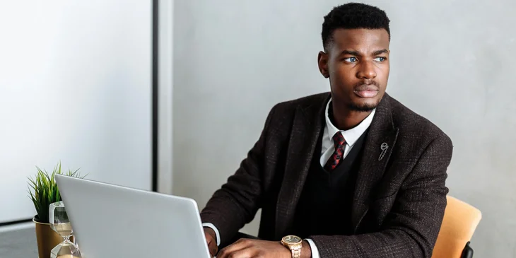 A man in black suit using a laptop.