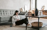 Une femme assise par terre avec son ordinateur portable, travaillant à domicile.