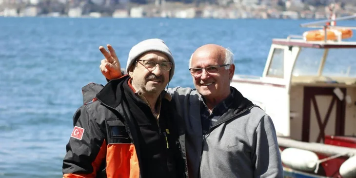 Two maritime workers smiling and working on a dock.