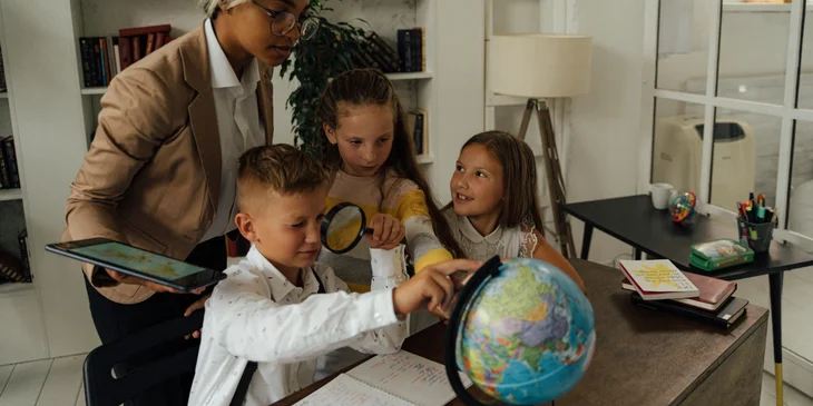 A social studies teacher discusses a lesson using a globe.