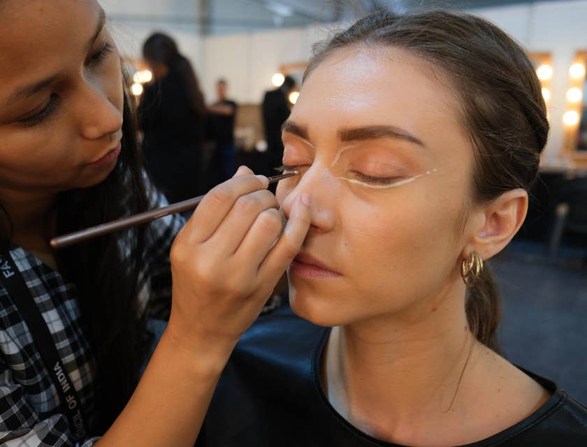 A special effects makeup artist applying makeup to an actor.
