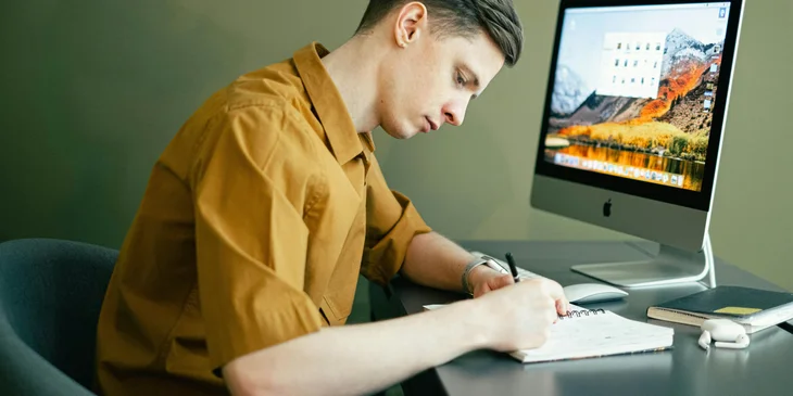 A man taking notes in front of his computer.