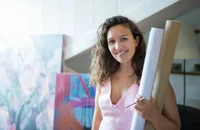 Eine lächelnde Frau hält aufgerollte Papierbögen.