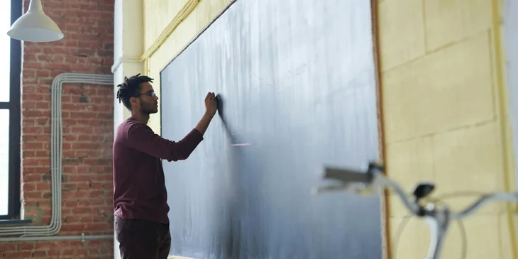 A substitute teacher writes his name on the board to introduce himself.