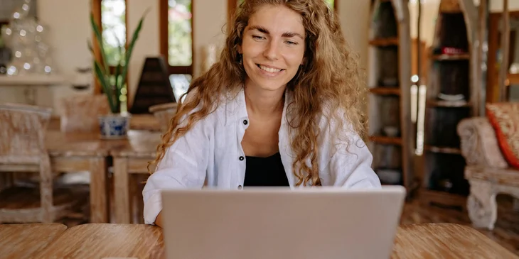 A woman smiling while using a laptop.