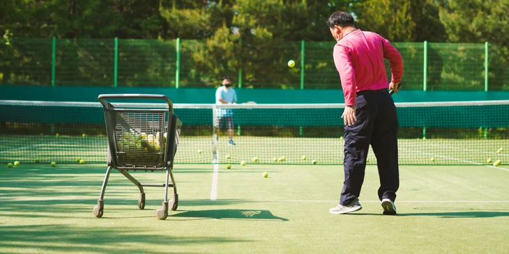 A tennis coach instructing a player on proper form and technique in tennis.