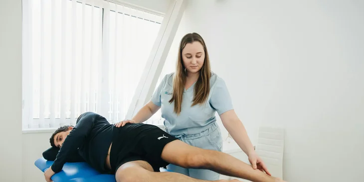 A physiotherapist examines a patient's leg during a therapy session.