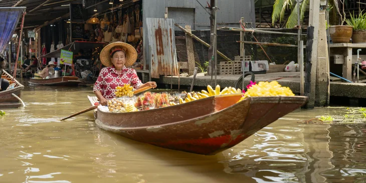A woman selling produce at a traditional floating market in Bangkok, Thailand.