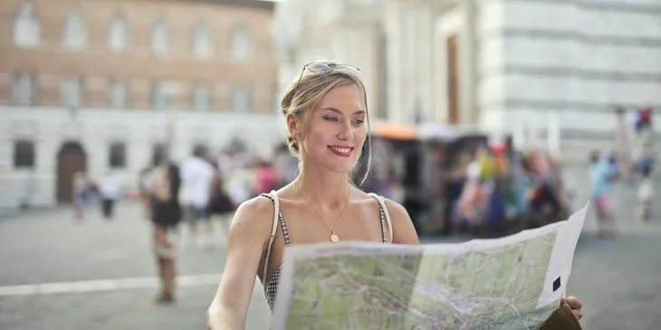 A woman holding a map looking for next destination.