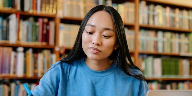 Una studentessa che studia al pc e sottolinea dei libri.