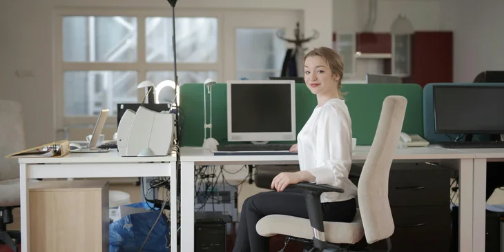 An elegant female employee sitting on a chair in a modern workplace.