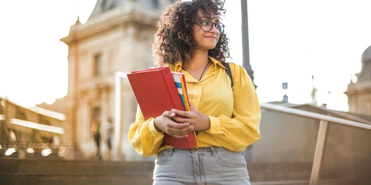 A student in yellow jacket holding books.