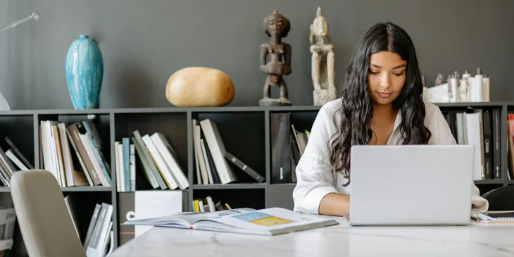 A freelancer sitting at a desk and working on a laptop.