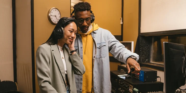 A man and a woman listening to a recording.