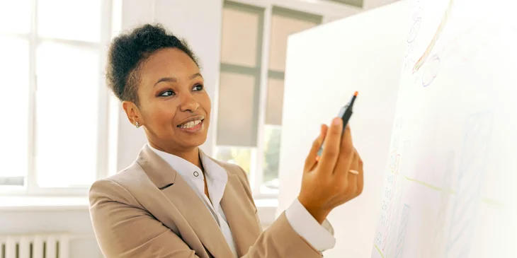 A woman presenting data on a whiteboard.