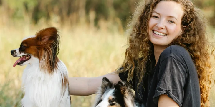 A woman with dogs resting near a field.