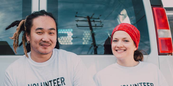 Two volunteers distributing boxes of aid supplies in their local community.