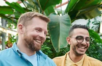 Zwei Mitarbeiter stehen vor einem Palmenblatt in dem Garten eines Büros.