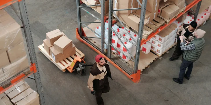 A warehouse associate pulling a trolley of boxes.