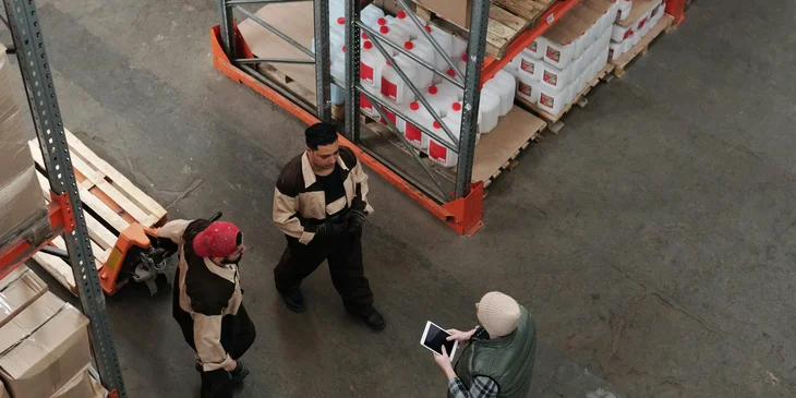 A warehouse manager checking with the staff about the products that have arrived.