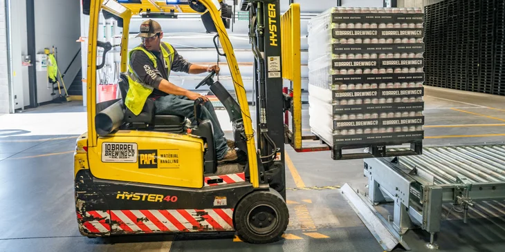 A forklift operator driving a forklift to move goods in a warehouse.