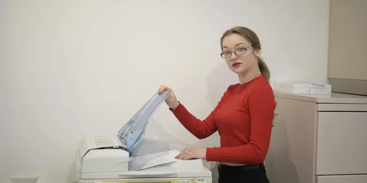 A woman using a printer in an office.