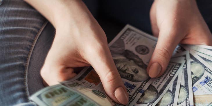 hands holding fanned out hundred dollar bills