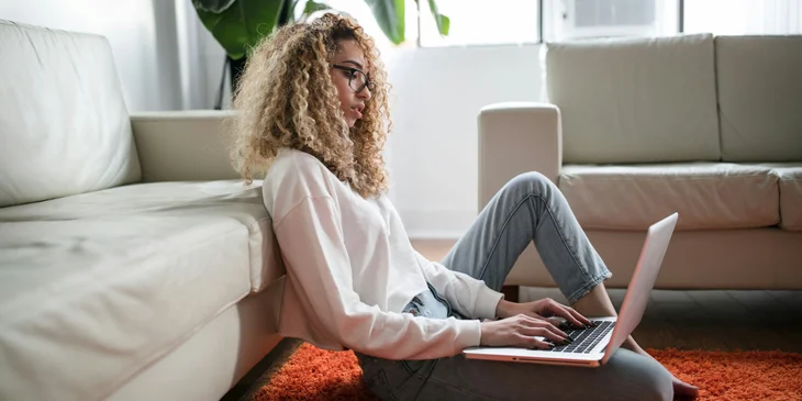 A woman on sabatical leave typing on the floor.