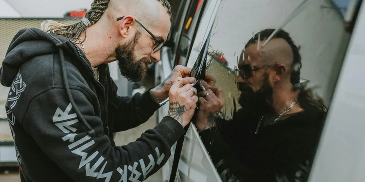 A man applying tint to a car window.