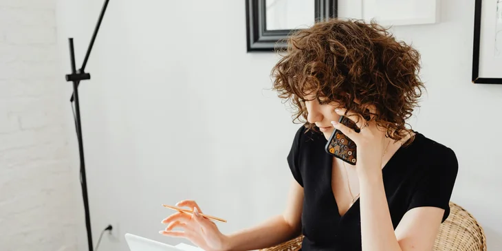 A woman speaking on the phone in her office.