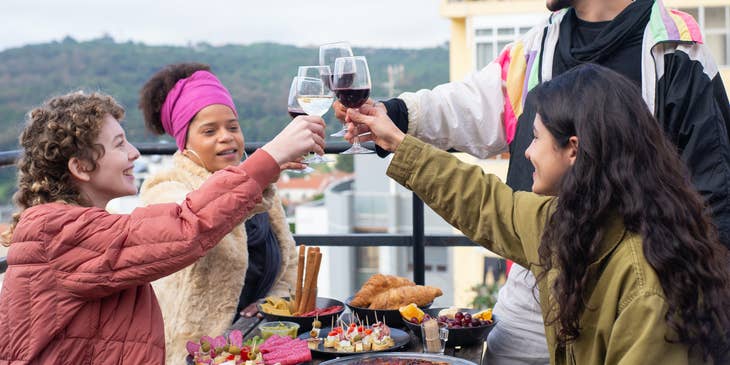 A group of friends doing a toast with wine glasses in an outdoor setting.