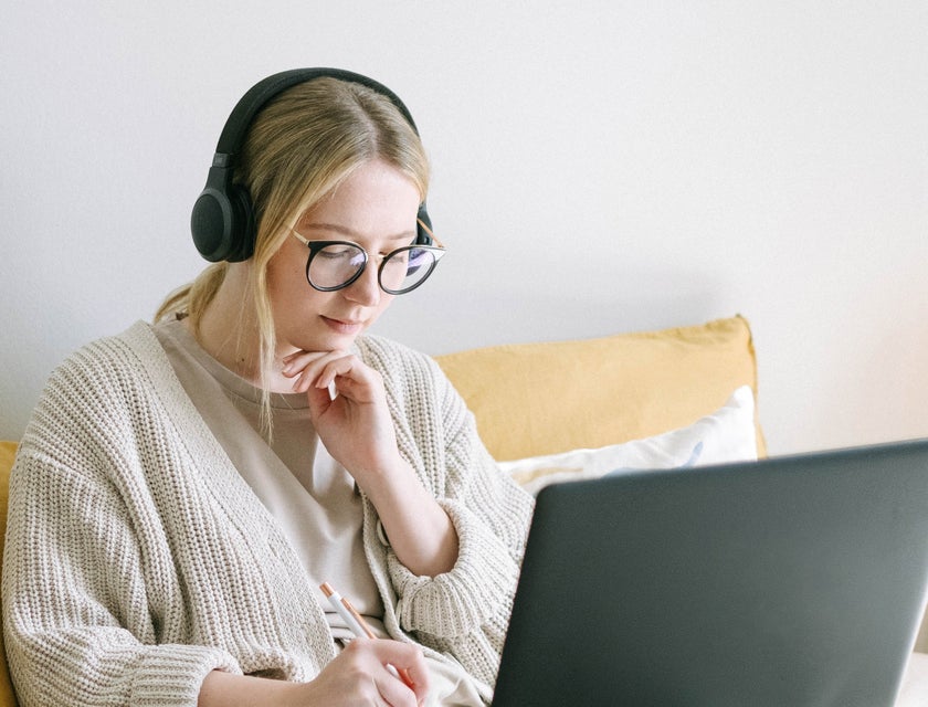 A woman working on a laptop on her couch in her home.