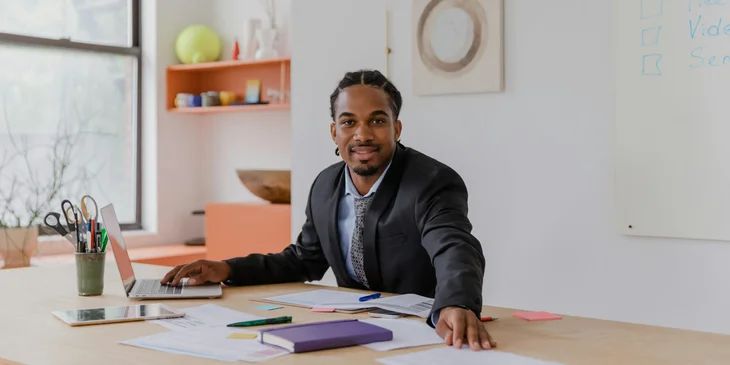 A man smiling while sitting at his desk.