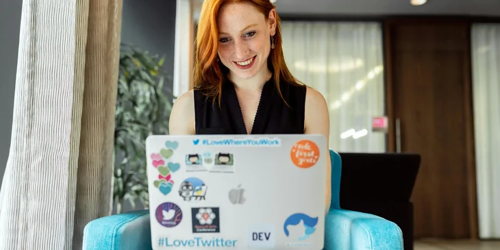 A woman in black tank top using a laptop.