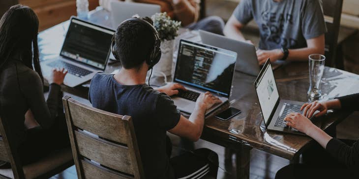 a team of Big Data Engineers working around the table on their respective laptops