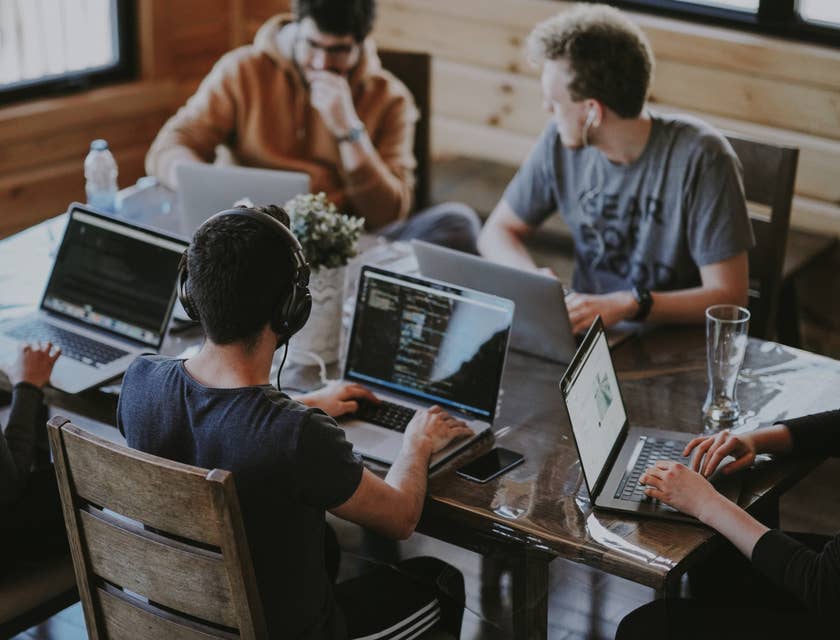 a team of Big Data Engineers working around the table on their respective laptops