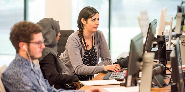 Bilingual Customer Service Representatives lined up along the desk working on their respective computers