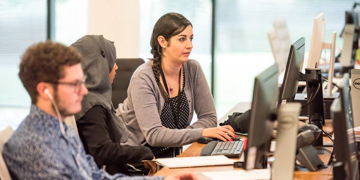 Bilingual Customer Service Representatives lined up along the desk working on their respective computers