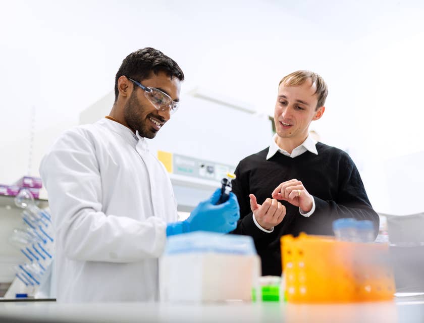 Biochemical Engineer conducting research in a laboratory and showing a vial to his assistant