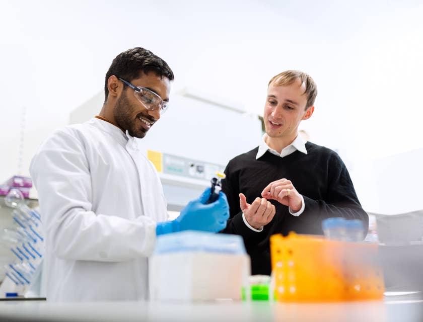 Biochemical Engineer conducting research in a laboratory and showing a vial to his assistant