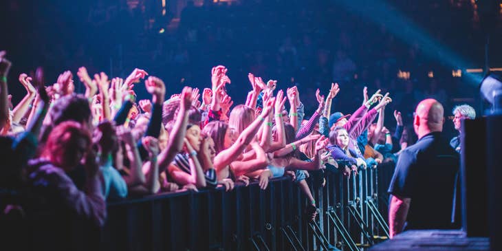 Bouncers stationed in front of the stage facing the crowd during an ongoing performance