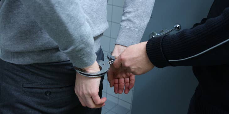 A Bounty Hunter on duty handcuffing a male fugitive he caught.