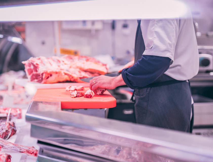 Butcher slicing raw meat as of customer's preference.