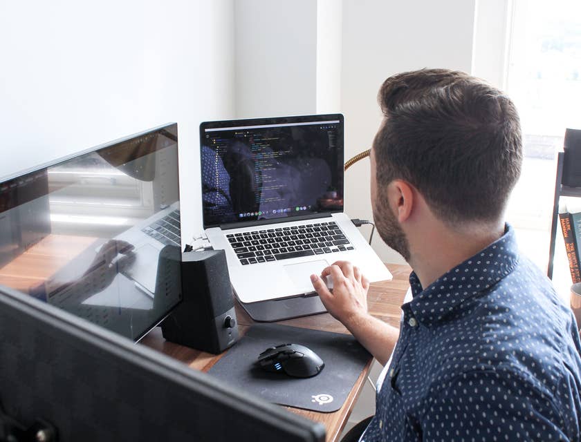 C++ Developer optimizing the software program on his laptop together with a desktop computer