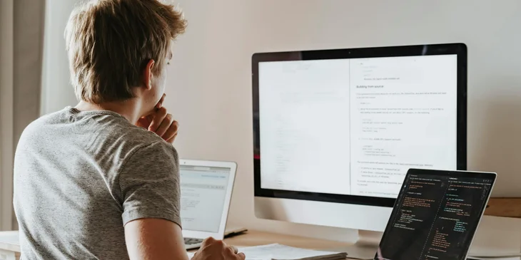 A C# developer sitting in front of his workstation and checking the details of the code he is working on.